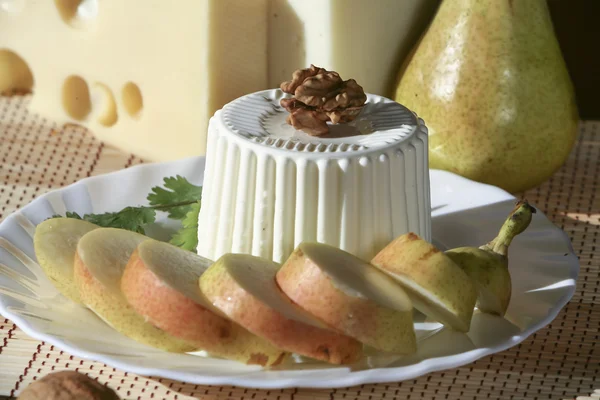 Fresh cheese and walnuts served with fruit on a white plate — Stock Photo, Image