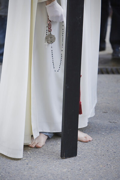 Barefoot penitent doing penance with a wood cross in a Holy week procession