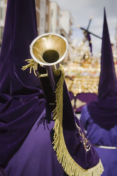 Penitent purple tunic holds a trumpet during Holy week procession — Stock Photo, Image