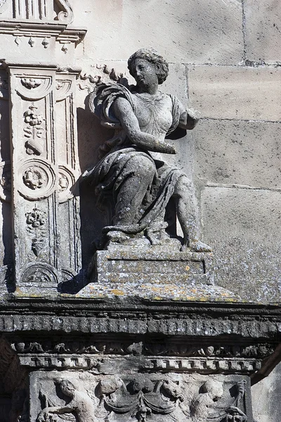 Figura femenina sentada sobre una pilastra y arco con decoración floral en la fachada principal de la capilla de El Salvador — Foto de Stock