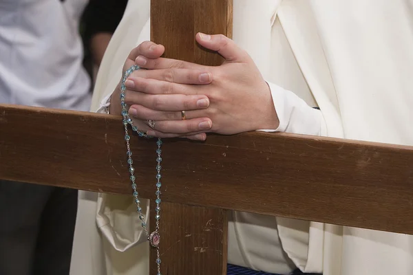 Penitent supports their hands crossed with a rosary on a wooden cross in holy week — Stock Photo, Image