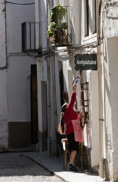 Mujer colgando un plato de cerámica en la puerta de una tienda de antigüedades — Foto de Stock
