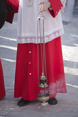 Acolyte supports censer in a procession of Holy Week clipart