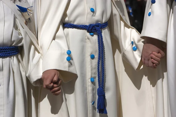 Penitents with white tunics gathers of the hand during a procession of Holy Week — Stock Photo, Image