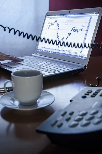 Close-up van de vrouwelijke oproep door telefoon vóór een laptop met een kopje koffie in het kantoor — Stockfoto