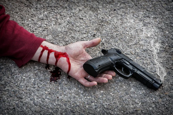 Man with gun in hand bloodstained lies dead in the asphalt murde — Stock Photo, Image