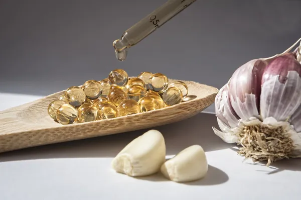 Glass dropper on capsules of garlic oil — Stock Photo, Image