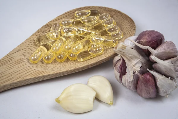 Capsules of garlic oil in a bucket of wood — Stock Photo, Image