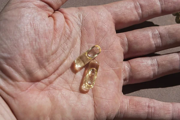 A hand holding garlic oil pills — Stock Photo, Image