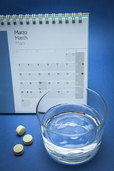 Verre d'eau et pilules isolé sur bleu — Photo