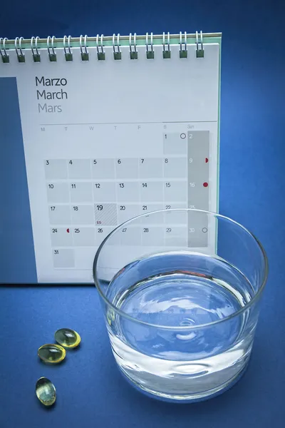 Glas med vatten och piller isolerade på blått — Stockfoto