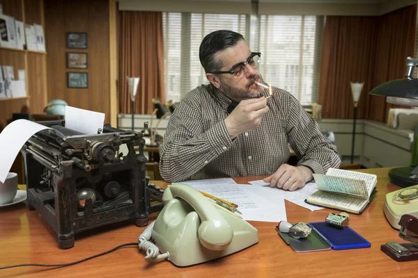 Mann raucht während der Arbeit im Büro eine Zigarette, Szene aus den 1960er Jahren — Stockfoto