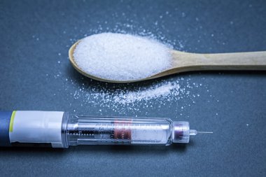 İnsülin Kalem ile birlikte bir yemek kaşığı mavi zemin üzerine beyaz şeker, hiperglisemi veya diyabet hastalığı kavramı