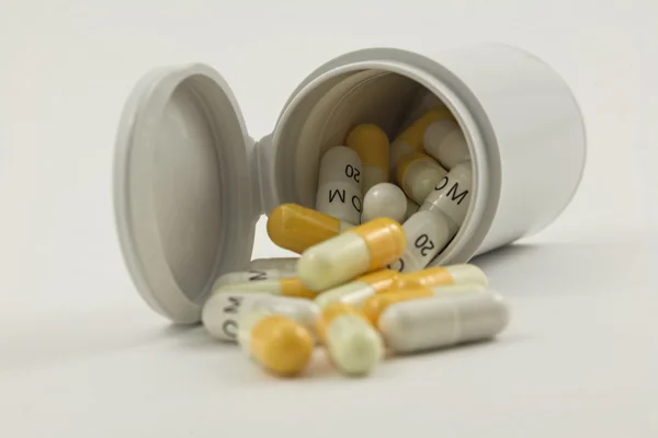 Bottle with white and yellow pills isolated on a white backgroun — Stock Photo, Image