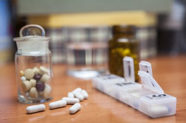 Old bottle of pills along with a few pills above a wooden table clipart
