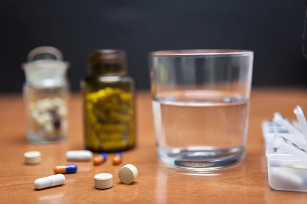 Oude fles pillen samen met een paar pillen boven een houten tafel — Stockfoto