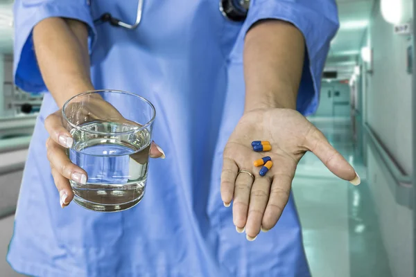 Picture of doctor hands giving blue and orange pills and glass o — Stock Photo, Image