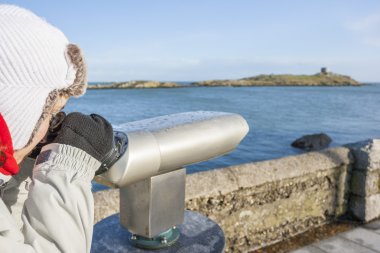 Woman looking to Dalkey island by binoculars clipart