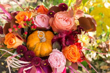 Kırmızı turuncu sonbahar buketi pembe gül çiçekleri, dökülen yapraklar ve balkabağı profesyonel çiçekçiler tarafından kapatıldı.