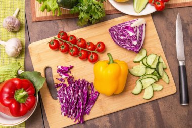 Sağlıklı vejetaryen diyet yemekleri pişirmek için farklı sebzeler. Mutfaktaki tahta tahtada salata için sebze kesiyorum.