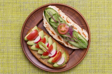 Vegan, vejetaryen tostları, farklı sebzeli bruschetta, avokado, domates, humus, salatalık, turp ve yeşillikler.