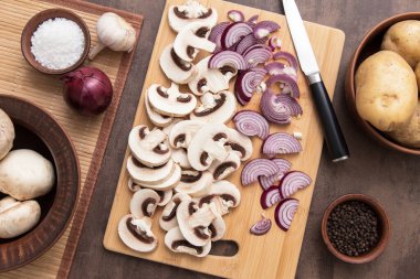 Kırmızı menekşe soğanlı dilimlenmiş mantar şampiyonu mutfaktaki tahta kesme tahtasında. Üst manzara, düz uzanma