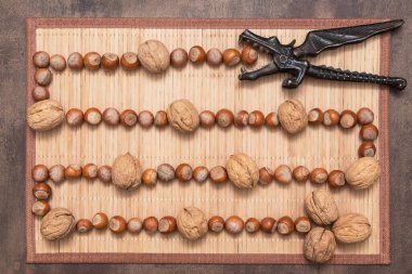 Ceviz, fındık ve fındık kıracağı kahverengi peçete arka planında, üst manzara, düz yatış. Farklı karışık fındık.