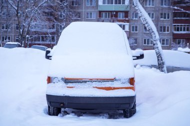 Turuncu araba, kardan sonra karla kaplı minibüs ve kışın kasabada kar fırtınası.