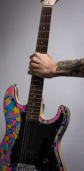 Bras tatoué tenant une guitare colorée — Photo