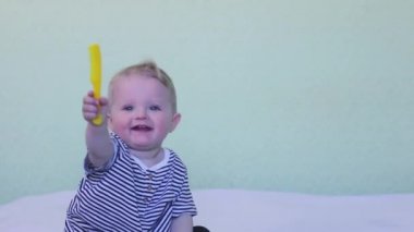 Portrait of a cute smiling baby who is combing his hair with a special brush. The concept of baby hygiene, childcare and health care, skills, independence