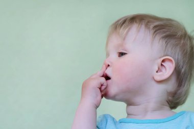 A small sick child rubs his nose, mucus flows. Treatment of snot in a child. Copy space - concept of health, colds, immunity, prevention, cleansing.