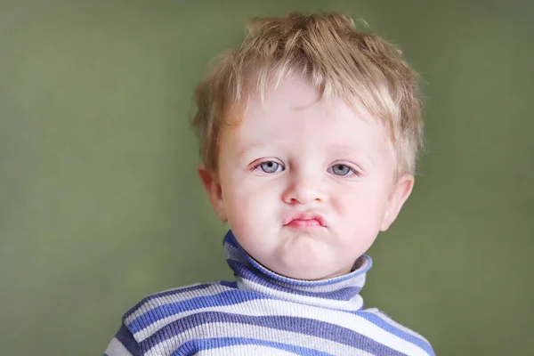 Disgruntled, angry child. A naughty difficult boy expresses dislike, frowns displeasedly. Copy space - concept of upset baby, neglect, disgust, childish irritability, bad behavior, negative feelings.