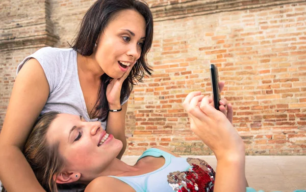 Dos hermosas mujeres mirando entusiasta en el teléfono móvil — Foto de Stock