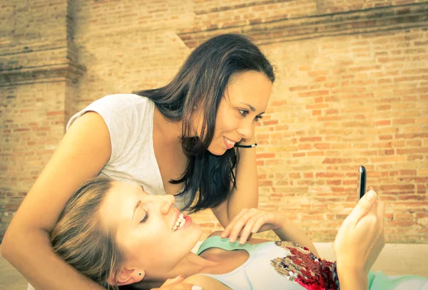 Dos hermosas mujeres mirando entusiasta en el teléfono móvil — Foto de Stock