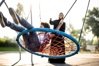 Emirliklerden bir kadının çocuklarıyla oyun parkında eğlenirken görüntüsü.