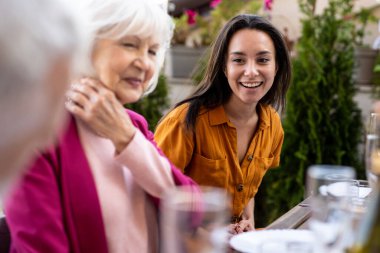 Çok ırklı bir grup insanın çatıda yemek yediğini gösteren görüntüler. Aile ve arkadaşlar evde bir araya gelir.