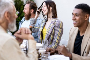 Çok ırklı bir grup insanın çatıda yemek yediğini gösteren görüntüler. Aile ve arkadaşlar evde bir araya gelir.
