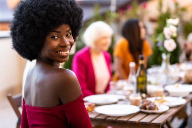 Çok ırklı bir grup insanın çatıda yemek yediğini gösteren görüntüler. Aile ve arkadaşlar evde bir araya gelir.