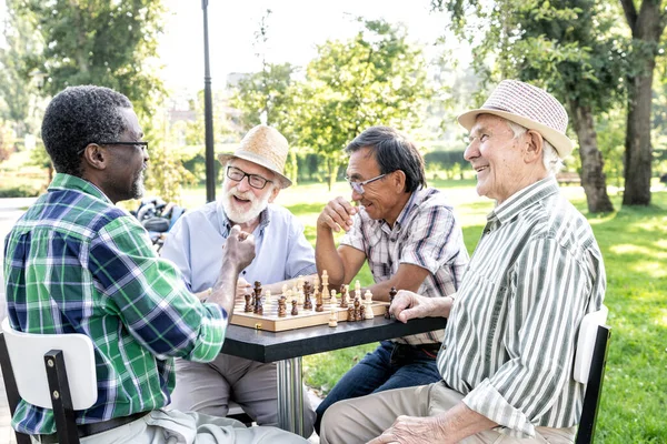 Grupo de amigos sênior jogando xadrez no parque. conceitos de estilo de  vida sobre antiguidade e terceira idade