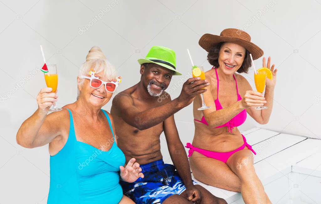 Happy seniors having party in the swimming pool - Elderly friends at a pool party during summertime