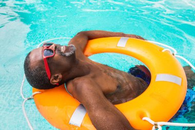 Mutlu son sınıf öğrencisi yüzme havuzunda parti veriyor. Aktif yaşlı erkek yazın güneşleniyor ve özel bir havuzda dinleniyor.