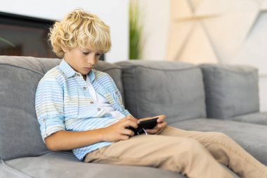 Evdeki akıllı telefonla video oyunlarında oynayan sevimli çocuk.