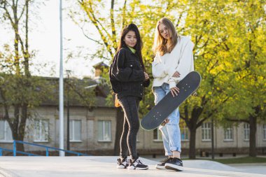 Açık havada kaynaşan ve şehir kaykay parkında toplanan havalı gençlerden oluşan çok kültürlü bir grup.