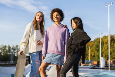 Açık havada kaynaşan ve şehir kaykay parkında toplanan havalı gençlerden oluşan çok kültürlü bir grup.