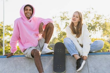 Açık havada kaynaşan ve şehir kaykay parkında toplanan havalı gençlerden oluşan çok kültürlü bir grup.