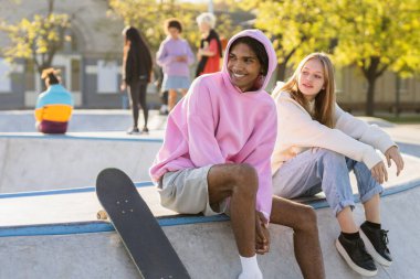 Açık havada kaynaşan ve şehir kaykay parkında toplanan havalı gençlerden oluşan çok kültürlü bir grup.