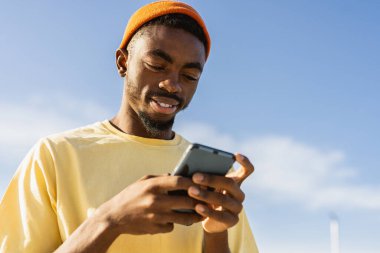 Akıllı telefon kullanarak kaykay parkında havalı bir genç kaykaycı.