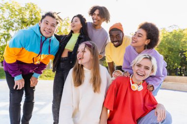 Açık havada kaynaşan ve şehir kaykay parkında toplanan havalı gençlerden oluşan çok kültürlü bir grup.