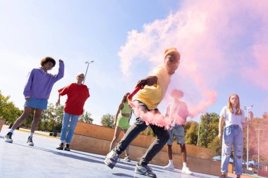 Açık havada kaynaşan ve şehir kaykay parkında toplanan havalı gençlerden oluşan çok kültürlü bir grup.