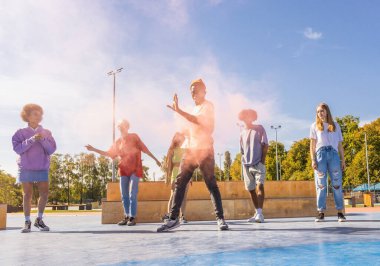 Açık havada kaynaşan ve şehir kaykay parkında toplanan havalı gençlerden oluşan çok kültürlü bir grup.